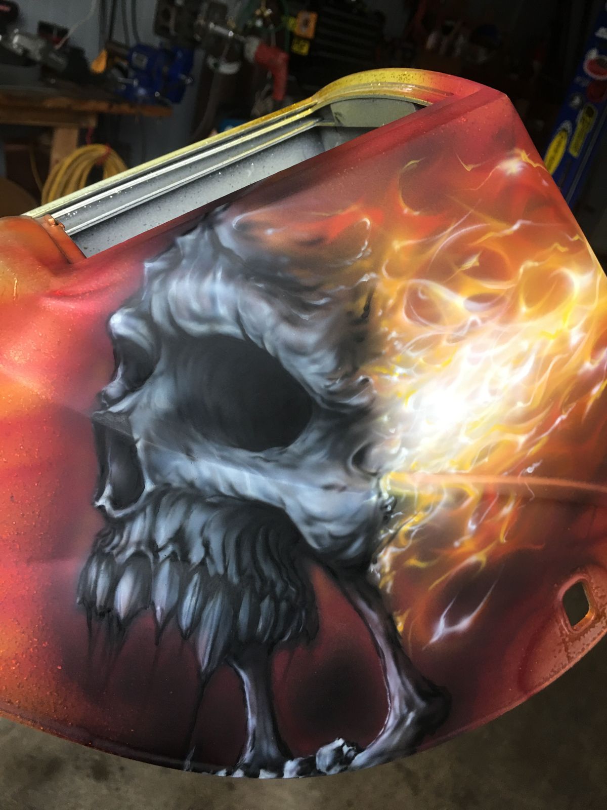 A curved fender painted orange-red with a large grey skull dissolving into bright yellow and white flames.